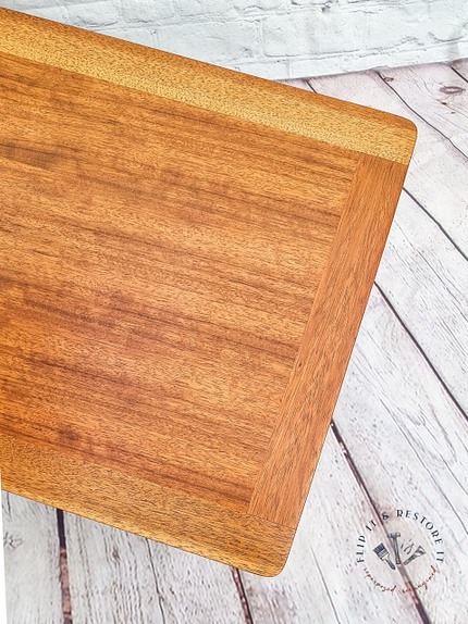 A G-Plan Librenza Mid Century Modern Black and Tola Vintage Coffee Table from the 1950's is set against a distressed white wooden floor and a white brick background. The logo and text "Find it Restore it" are visible in the lower right corner.