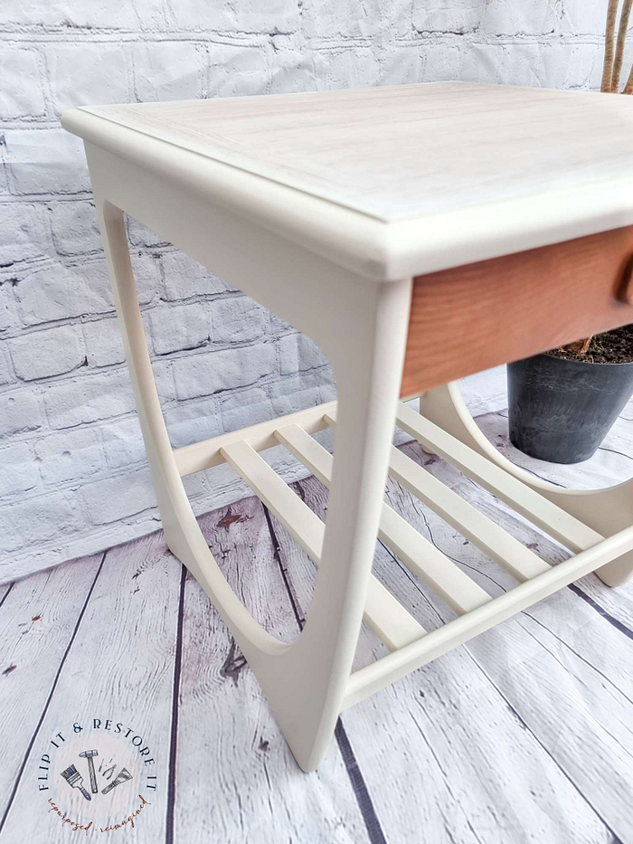 A beautifully restored vintage drinks cabinet from the 1960s, labeled as the Mid Century Beautility Drinks Cabinet, is styled against a white brick wall on light wooden flooring. Featuring a walnut finish that exudes classic elegance, the cabinet showcases meticulous craftsmanship iconic of its era. The "Flip It & Restore It" logo is prominently displayed on the floor next to this sophisticated piece.