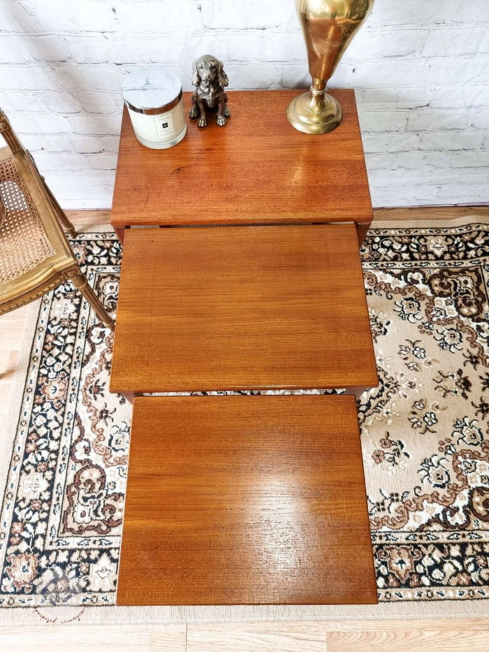 An Ercol Saville Ash Long Coffee Table with Smoked Glass Mid Century Vintage is positioned on a decorative rug. On its surface, there is a bronze dog figurine, a brass vase, and a candle. To the side, part of a wooden chair with a woven seat is visible.